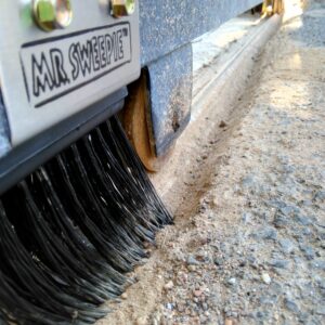 Mr. Sweepie® brush kit installed on sliding gate track - sweeps debris, protects gate motor.