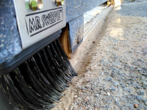 Mr. Sweepie® brush kit installed on sliding gate track - sweeps debris, protects gate motor.